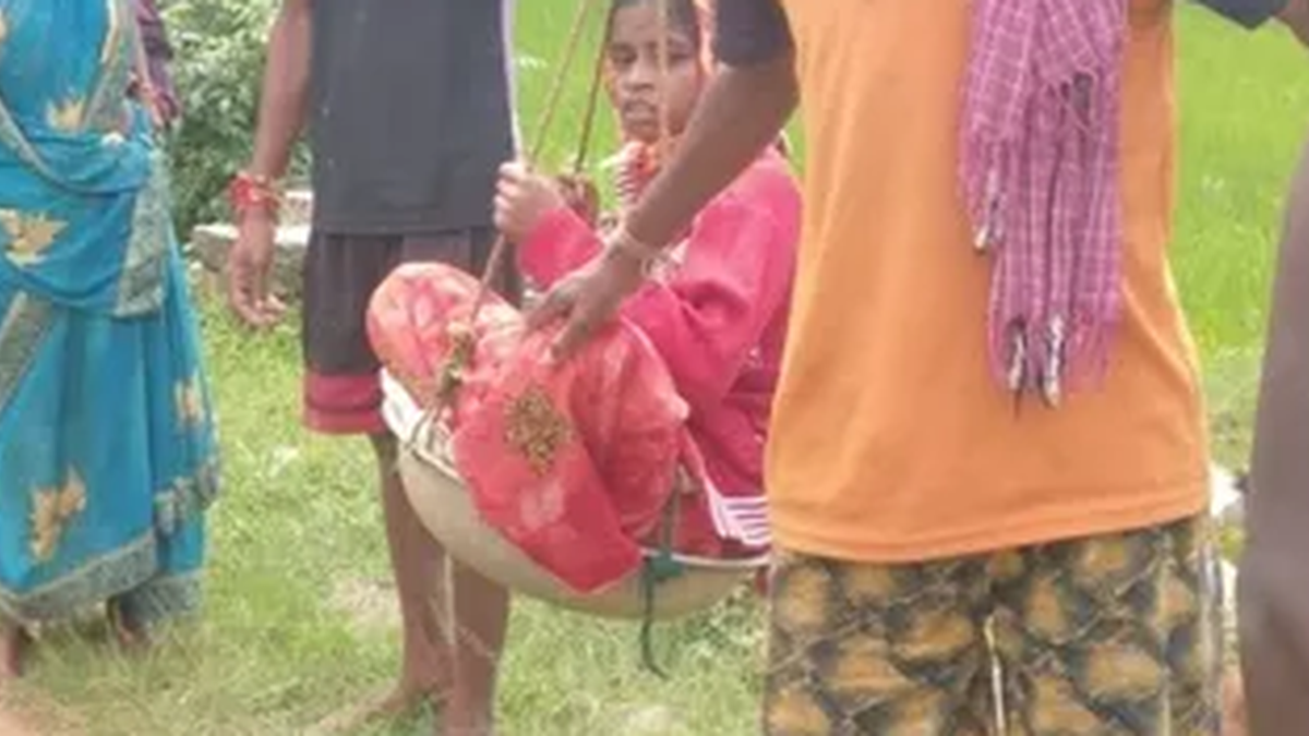 बेन्दवाकोना गांव में गर्भवती महिला को खाट पर मुख्य सड़क तक ले जाते ग्रामीण