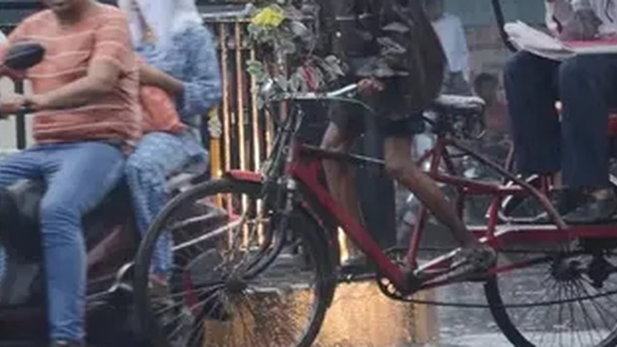धनबाद में बारिश के बीच सड़क से गुजरते राहगीर